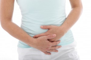 Cropped view of the hands of a woman with stomach pain clutching her stomach, isolated on white